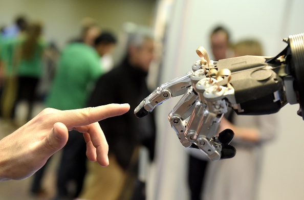A man moves his finger toward SVH (Servo Electric 5 Finger Gripping Hand) automated hand made by Schunk during the 2014 IEEE-RAS International Conference on Humanoid Robots in Madrid on November 19, 2014. The conference theme 