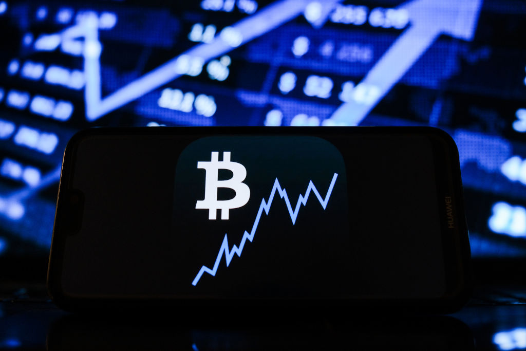 POLAND - 2021/02/08: In this photo illustration a Bitcoin logo seen displayed on a smartphone with the stock market graphic in the background. (Photo Illustration by Omar Marques/SOPA Images/LightRocket via Getty Images)