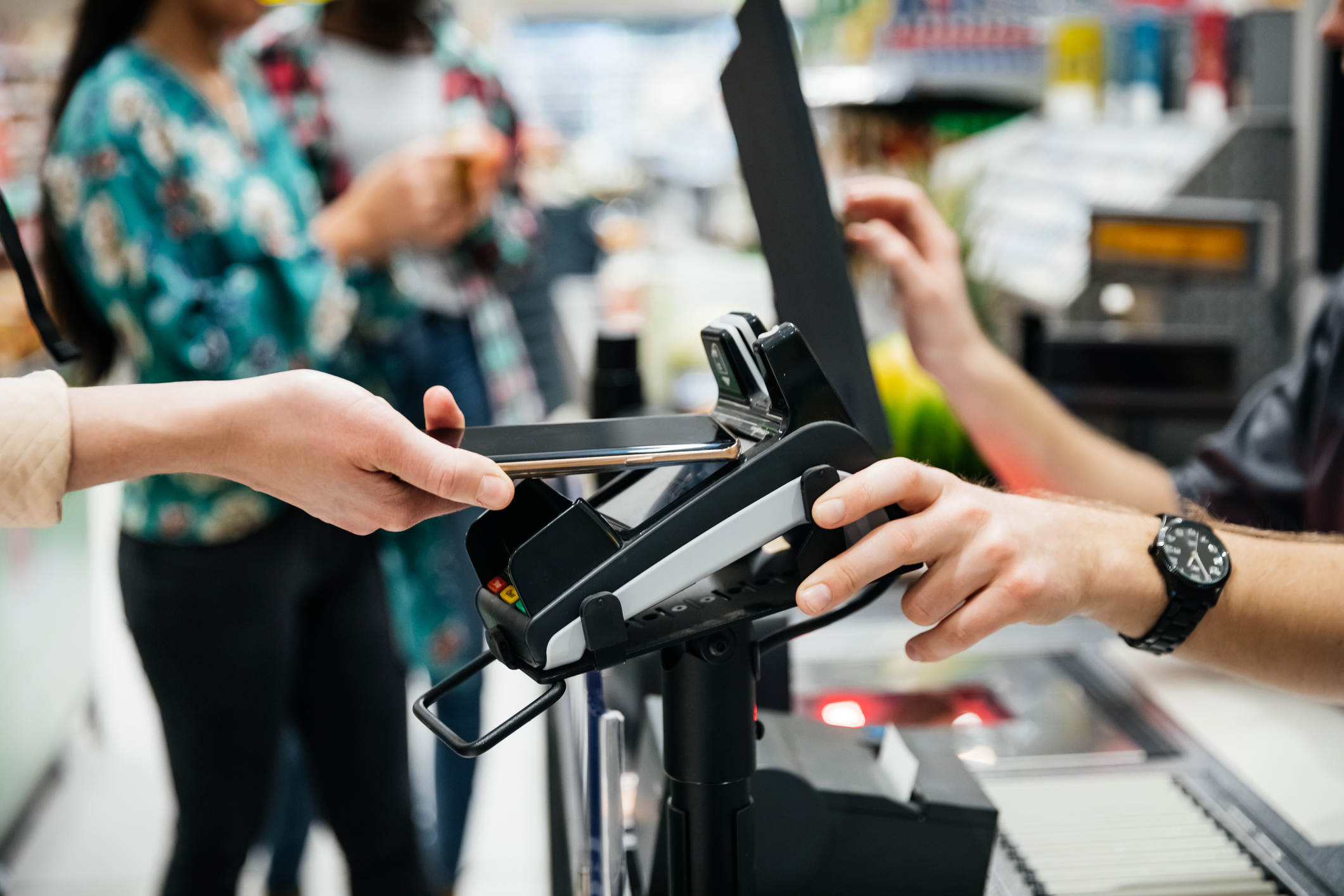 A close up of a contactless payment being made using a smartphone at the supermarket.