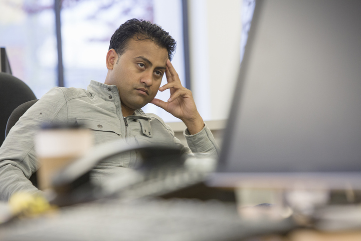 Asian businessman thinking at desk in office