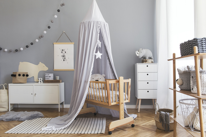 Cute modern interior of playroom with white walls, baby accessories and toys. Scandinavian child room with mock up poster frame.