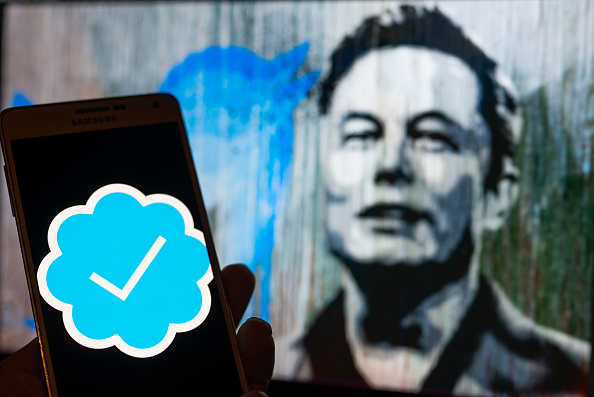Twitter Verified icon seen on mobile screen with Elon Musk in the background illustration, in Brussels, Belgium, on December 11, 2022 (Photo illustration by Jonathan Raa/NurPhoto via Getty Images)