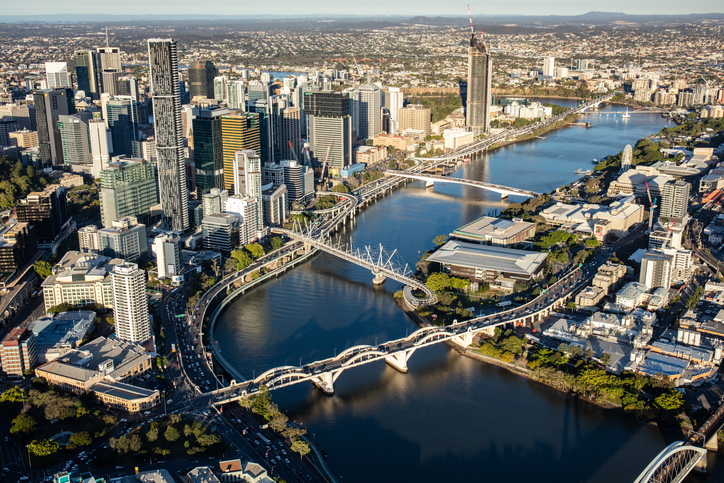 A view of Brisbane city from a helicopter. The Brisbane River can be seen winding its way through the heart of the city with several of the bridges that connect the north and south sides of the city.