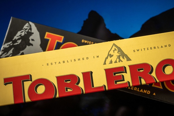 A picture taken on March 6, 2023, shows packagings of Toblerone chocolate bars owned by US firm Mondelez with a representation of the Matterhorn mountain (back) and of a generic mountain (front) in Geneva. - Toblerone is to remove the Swiss iconic Matterhorn peak from its packaging when some of the chocolate's production is moved from Switzerland to Slovakia and replaced by a more generic mountain under strict 