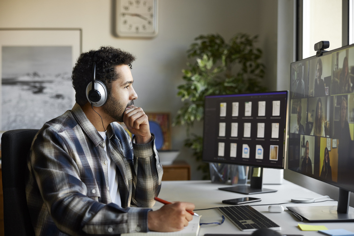 Businessman with headphones discussing during video conference. Multiracial male and female colleagues are attending online meeting. Entrepreneur is at home office.