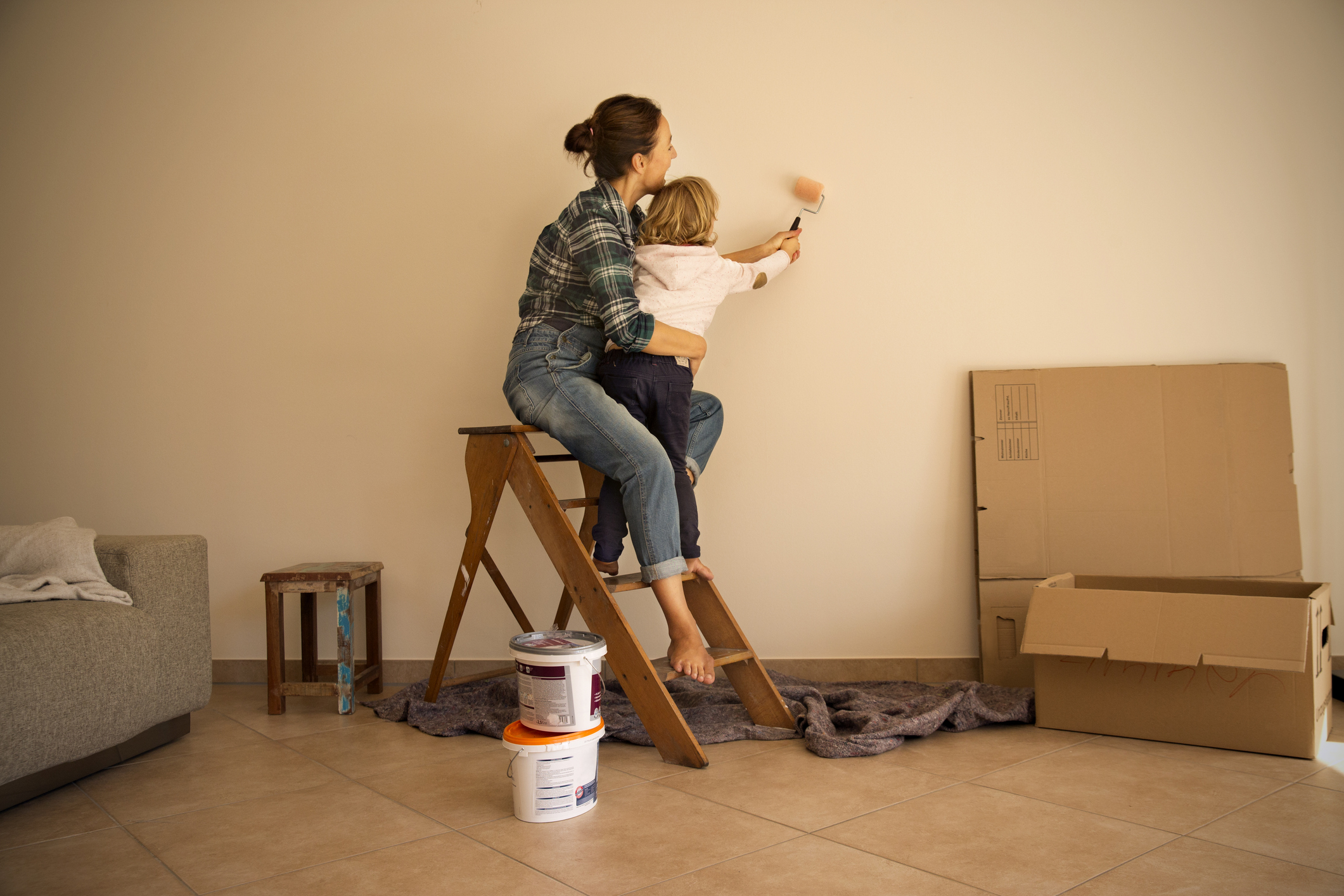 Deutschland, Mutter und Tochter auf der Leiter im Wohnzimmer streichen gemeinsam die Wand