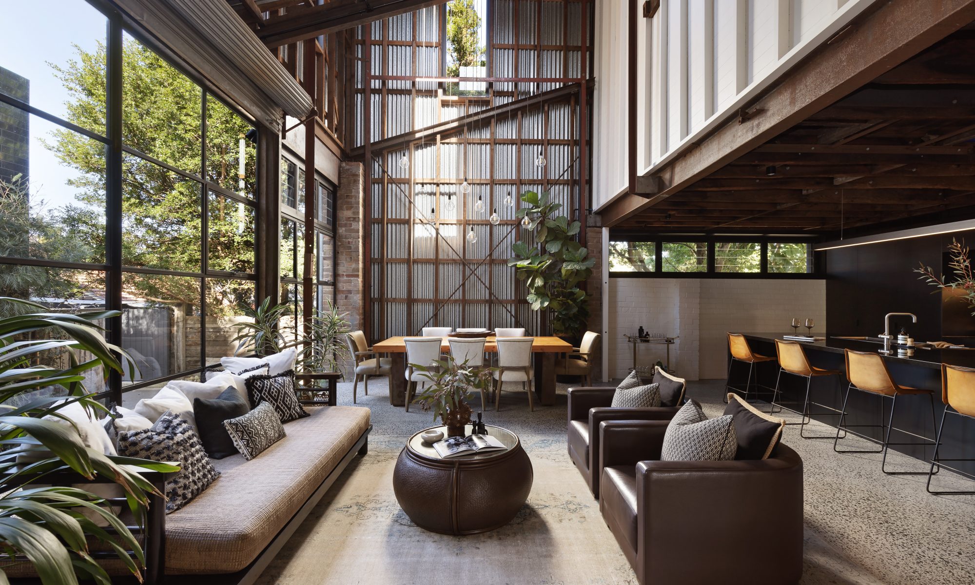 An open plan industrial kitchen, dining and living space with high ceilings.